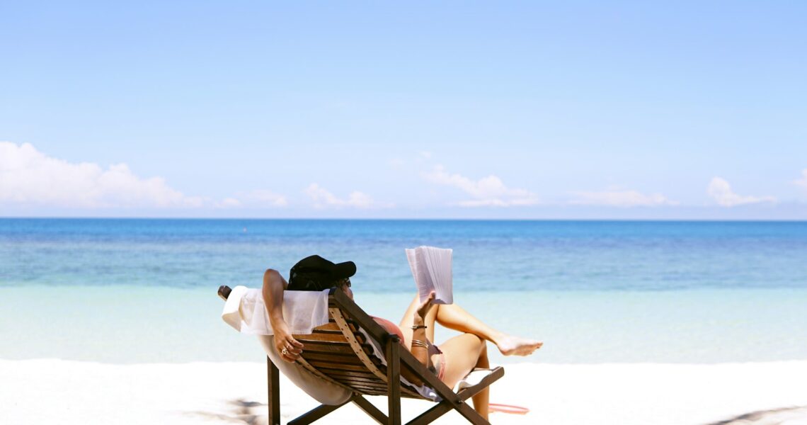 Femme assise sur une chaise de plage face à la mer en été